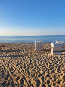 drie stoelen op een zandstrand bij de oceaan bij Ferienwohnung Daliah in Wangels