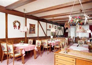 uma sala de jantar com mesas, cadeiras e lustres em Hotel-Pension Bergkranz em Braunlage