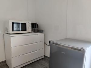 a microwave sitting on top of a dresser next to a refrigerator at Stop Stay at The Osterley! in Swansea