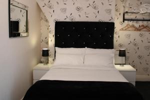 ブラックプールにあるMardonia Hotelのベッドルーム1室(大型ベッド1台、黒いヘッドボード付)