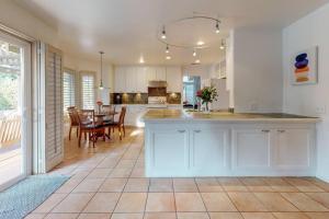 a kitchen with white cabinets and a dining room with a table at Sunset Disco: Large Pool/Spa @ Lush Family Retreat in La Quinta