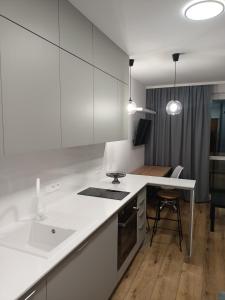 a kitchen with white cabinets and a table and a counter at DROINVEST Apartament Jarzębinowa - Wrocław KRZYKI - PKP - UE in Wrocław