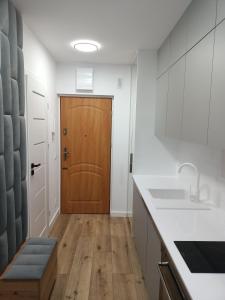 a kitchen with white counters and a wooden door at DROINVEST Apartament Jarzębinowa - Wrocław KRZYKI - PKP - UE in Wrocław