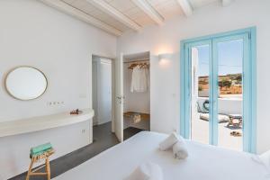 Habitación blanca con cama y espejo en Blue Harpist Villas, en Koufonisia