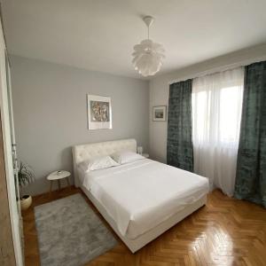 - une chambre avec un lit blanc et une fenêtre dans l'établissement Apartman Sanja, à Banja Luka