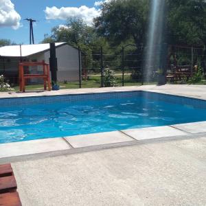 a swimming pool with blue water and a fountain at Susurro de Montaña (TIERRA SANTA) in San Lorenzo