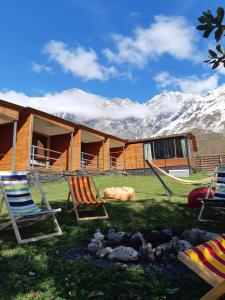 ein Resort mit Stühlen und ein Gebäude mit Bergen im Hintergrund in der Unterkunft Kazbegi Cottages in Kazbegi