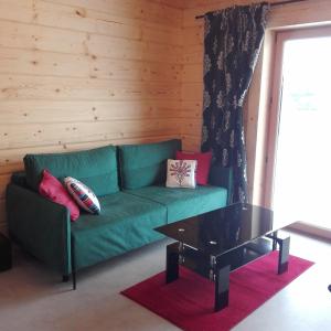 un sofá verde con almohadas y una mesa de centro en una habitación en DOMEK NA WIERCHU en Kluszkowce