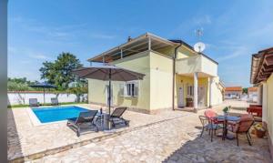 a house with a pool and a table with chairs and an umbrella at Apartments EDEN in Šišan