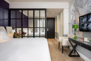 a bedroom with a white bed and a desk and a bed at Hotel Indigo Tel Aviv - Diamond District, an IHG Hotel in Tel Aviv