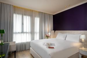a bedroom with a large white bed and a large window at Hotel Indigo Tel Aviv - Diamond District, an IHG Hotel in Tel Aviv
