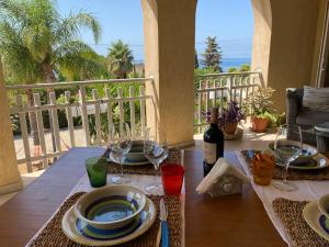 a table with plates and wine glasses on a balcony at Casamare San Giorgio in Sciacca