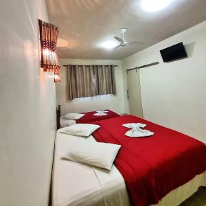 um quarto com 2 camas com cobertores vermelhos e almofadas brancas em NC Hotel em Bragança Paulista
