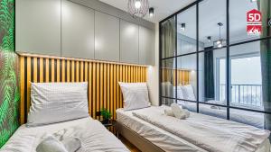two beds in a room with a window at Apartament Plant Luxe z Sauną ogólnodostępną - 5D Apartamenty in Świeradów-Zdrój