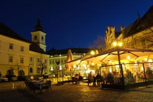 una piazza cittadina con tavoli e ombrelloni di notte di Historical Center Residence - Old Town Sibiu a Sibiu