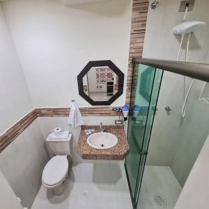 a bathroom with a toilet and a sink and a mirror at NC Hotel in Bragança Paulista