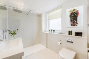 a white bathroom with a toilet and a sink at Explore the MOST EXQUISITE West-End from a Harrods FAMILY and COUPLE HOME in London