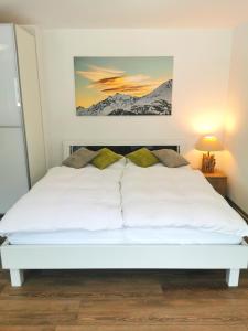 a bedroom with a white bed with a painting on the wall at Studio Rämschfädra in Sankt Niklaus