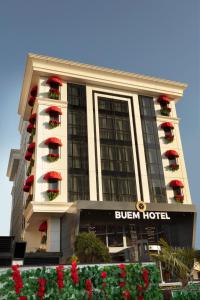 a hotel building with red flowers in front of it at Buem Hotel Koşuyolu in Istanbul