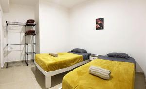 two beds in a room with yellow sheets at Angels Beach Condo con Piscina, Parking y Parque in Playa del Carmen +17 photos