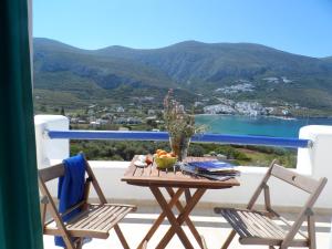 a table with a bowl of fruit and two chairs on a balcony at Amorgi Studios in Aegiali
