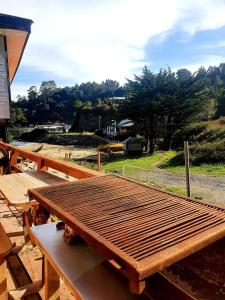 a wooden picnic table sitting on top of a deck at Borde Mar, Hostal & Cabañas, Bahía Mansa in Bahía Mansa