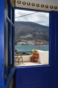 a blue door with a view of the ocean from a balcony at Amorgi Studios in Aegiali