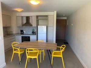 a kitchen with a wooden table and yellow chairs at Green Life Full Amenities in Punta del Este