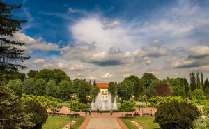 einen Brunnen inmitten eines Parks mit einem Gebäude in der Unterkunft Apartment Ekatarina in Banja Koviljača