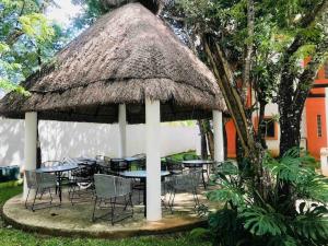 a group of tables and chairs under a thatch roof at Amazing 3 bedroom apartment with great pool in Cancún