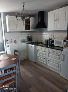 a kitchen with white cabinets and a table and a microwave at La petite maison du Quai in Blois