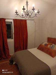 a bedroom with a bed with red curtains and a chandelier at La petite maison du Quai in Blois