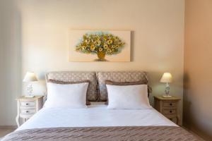 a bedroom with a bed with white sheets and a painting at Maisonette Elena in Longos