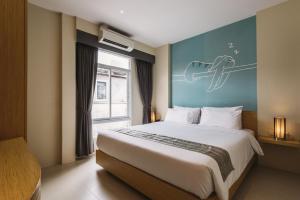 Un dormitorio con una cama grande con un cuadro en la pared. en TIRAS Patong Beach Hotel, en Patong Beach