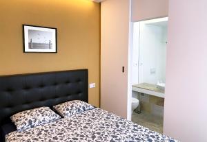 a bedroom with a bed with a black headboard and a sink at Casa Miradouro Apartments in Setúbal