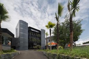 a building with palm trees in front of a street at Nindya Biodistrict Hotel Bandung in Bandung