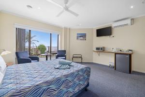 a bedroom with a bed and chairs and a television at Navigators Motel in Port Lincoln