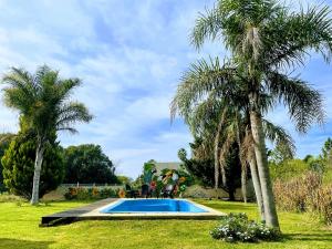 a swimming pool in a yard with two palm trees at RIBERAS DEL RÍO in Oliveros
