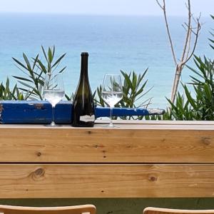 una botella de vino sentada en una mesa con copas en סוויטת כוכב הים ומרפסת גן מול גלי הים ומדרגות ישר לחוף העונות en Netanya