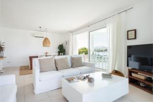 a white living room with a white couch and a tv at NEW! Villa ESPERANZA, Can Marilla, Front Sea View, Pool, AC, BBQ in Portocolom