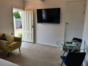a living room with a glass table and a television on the wall at Tourist Road - Studio Unit - Wi-Fi in Toowoomba