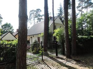 une maison blanche avec un portail dans les bois dans l'établissement holiday home, Morzyczyn, à Morzyczyn