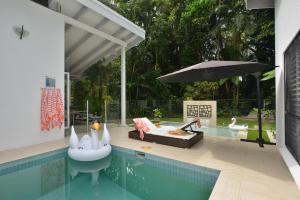 a house with a swimming pool with an umbrella at Pavilions in the Palms Heated Pool Short Path To Beach Five Bedrooms Sleeps 14 in Port Douglas