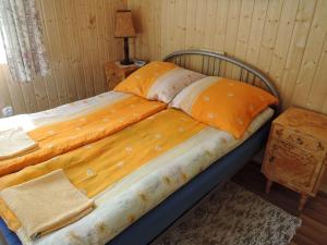 a bed with orange and white sheets on it at Holiday resort, Wiselka in Wisełka