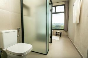 a bathroom with a toilet and a glass shower door at Pousada Casa Bambu in Cunha