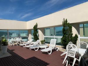 a group of white chairs and tables on a patio at Lindo flat no Guarujá in Guarujá