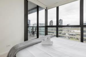 a bedroom with a bed and large windows at KULA Docklands in Melbourne