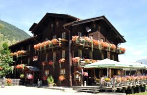 a large building with flowers in front of it at Swiss Lodge Joopi in Reckingen - Gluringen