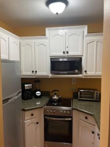a kitchen with white cabinets and a stove and microwave at Castle by the Shore in Ocho Rios