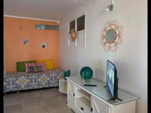 Una sala de estar con un sofá y un escritorio con televisión. en La villa ô plaisir, en Deshaies